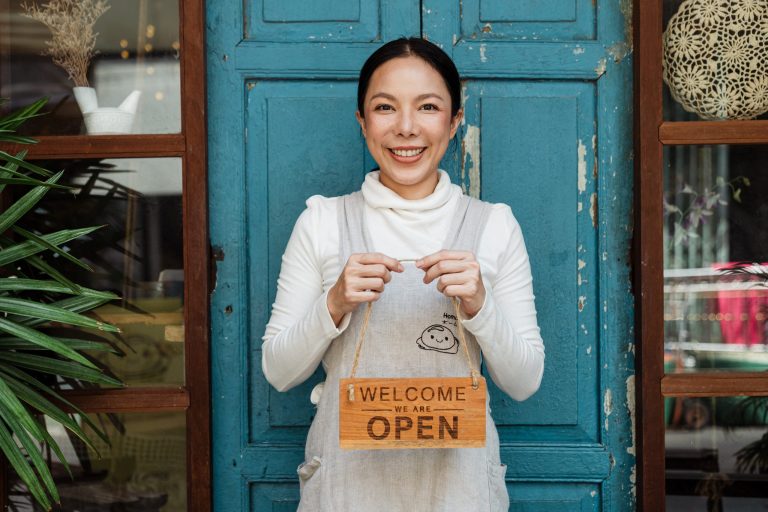 Small business owner holding an 'Open' sign.